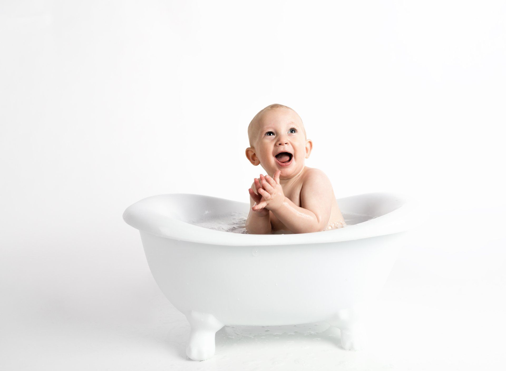 A baby is taking a bath in a white bathtub.