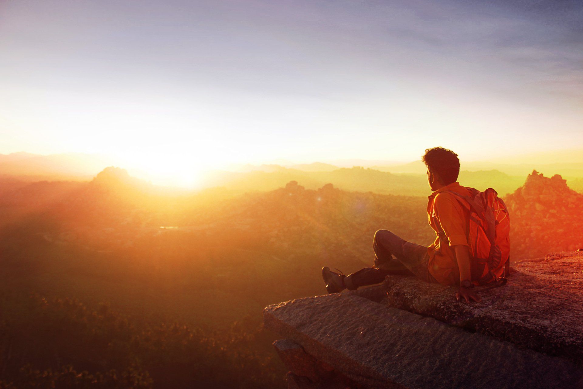 man on mountain top with sun