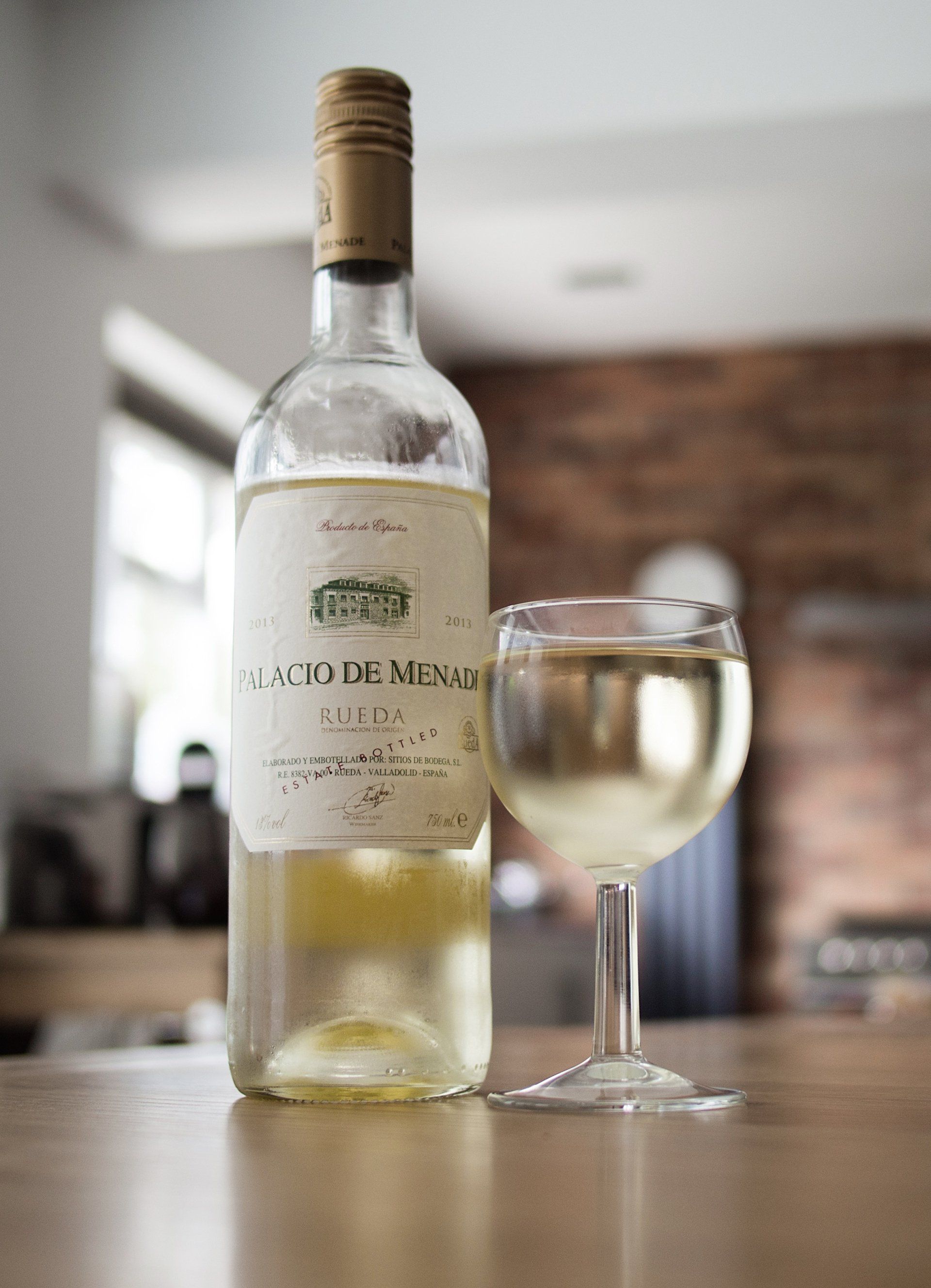 A bottle of white wine and a glass of white wine on a table.