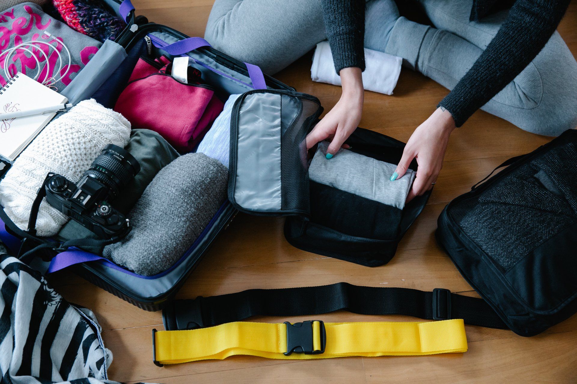 a woman is sitting on the floor packing a suitcase .