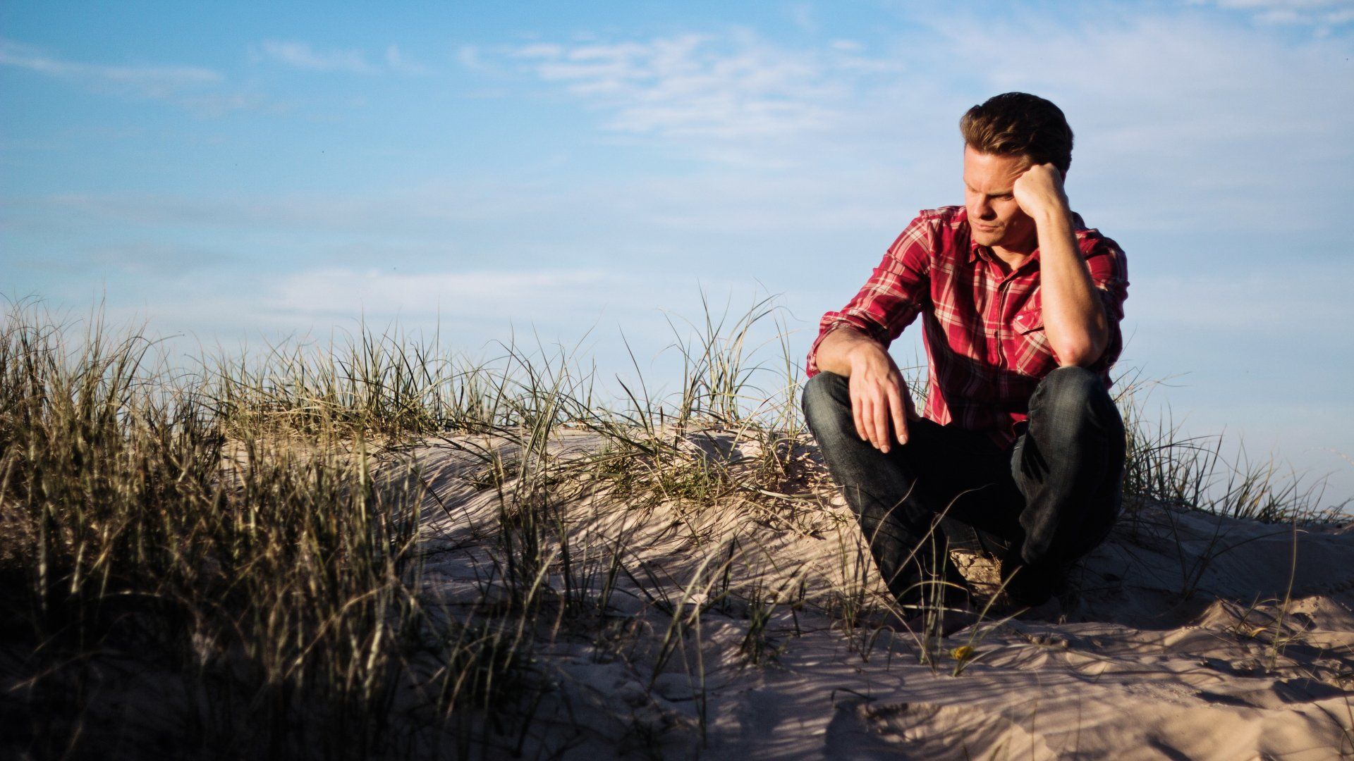 man alone sitting on grassy hill