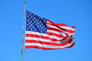 American flag waving on a flagpole against a clear blue sky
