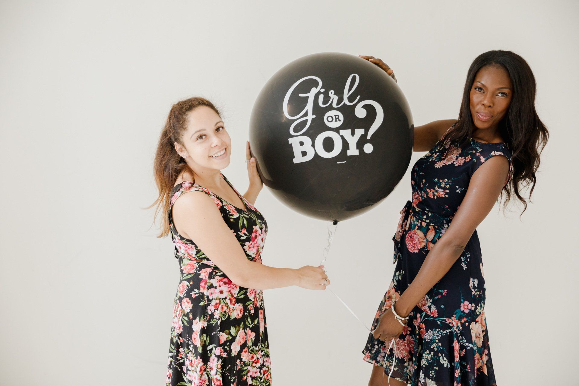 Two women holding a large black balloon that says