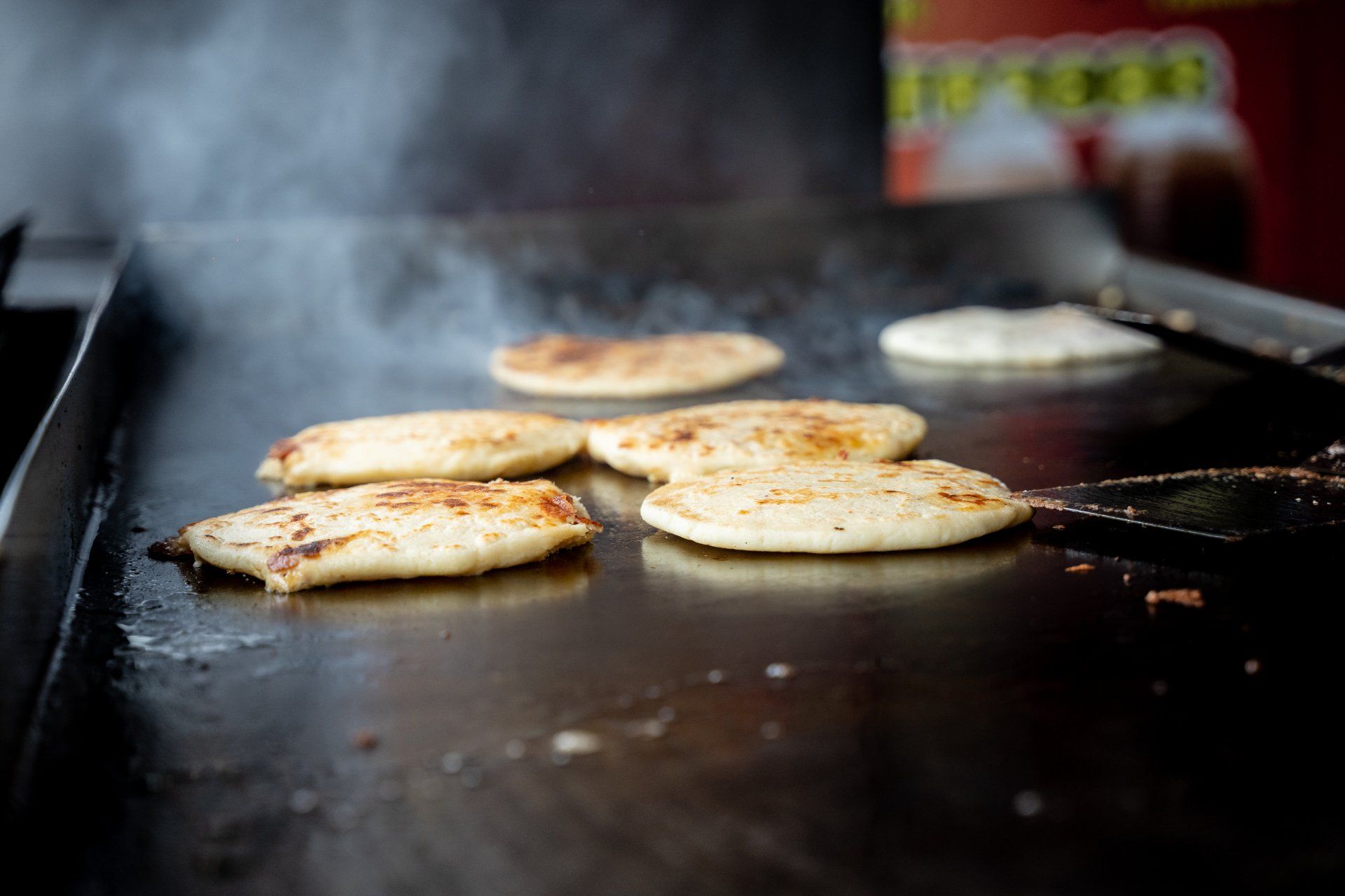 A person is cooking food on a grill with a spatula.