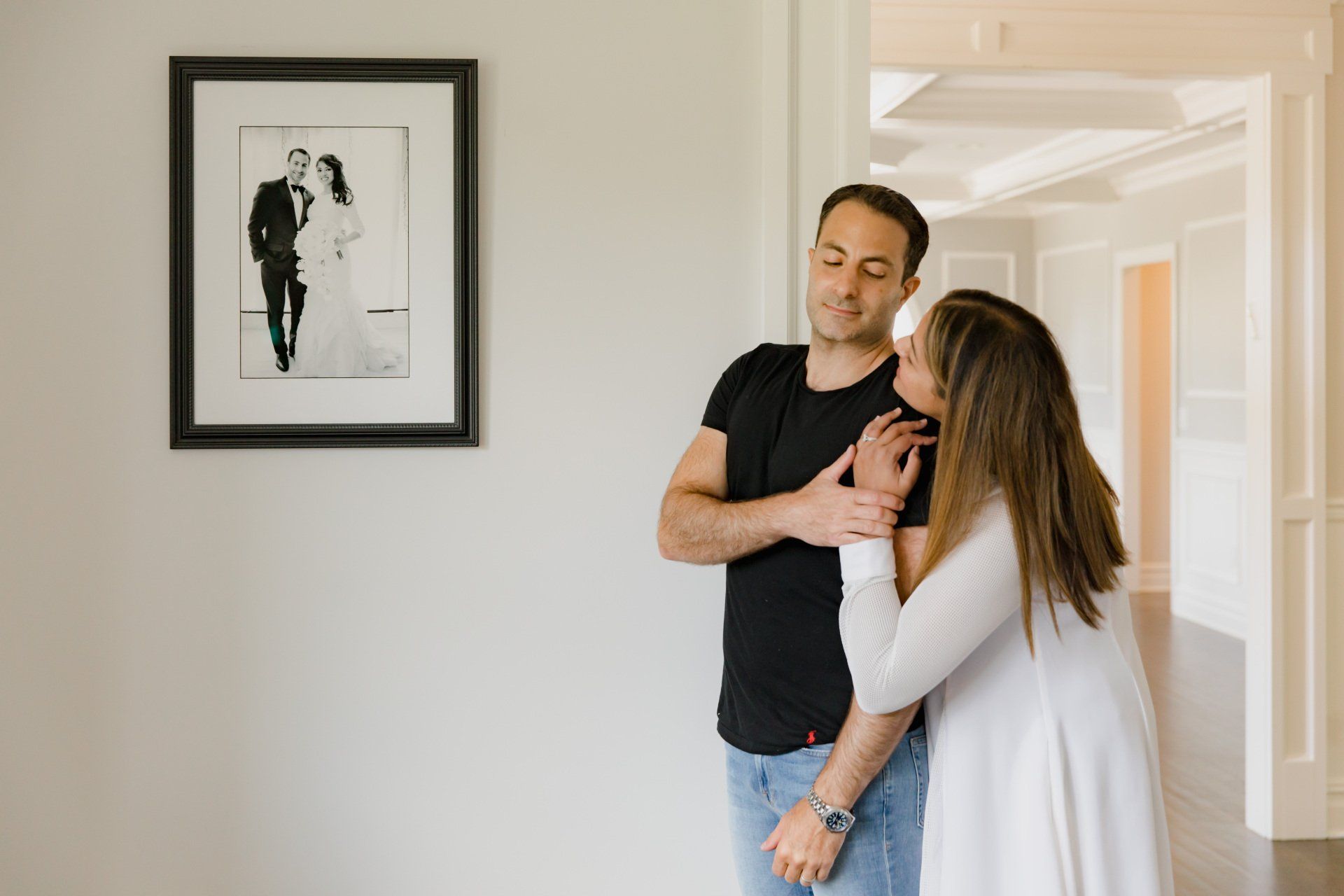 A man and a woman are standing in front of a framed picture of a bride and groom.