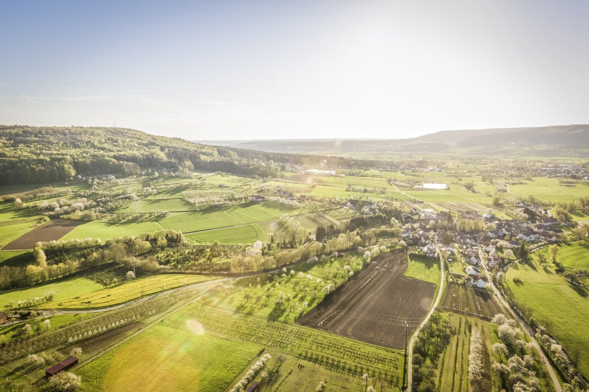 An aerial view of a lush green valley with a village in the distance.