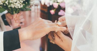 A bride and groom are putting on their wedding rings.