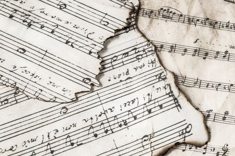 A sheet of music has a hole in the middle of it