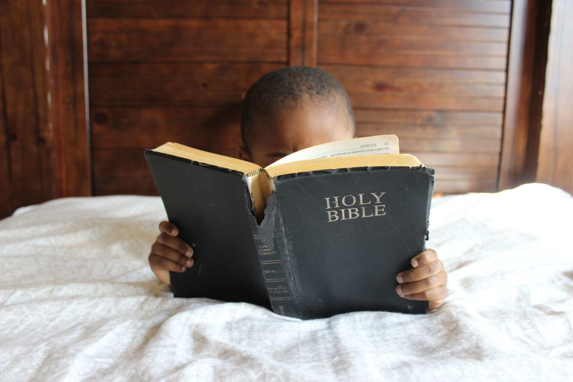 child reading the Bible in bed