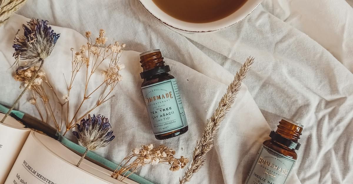 two bottles of essential oil are sitting on a bed next to a cup of coffee .