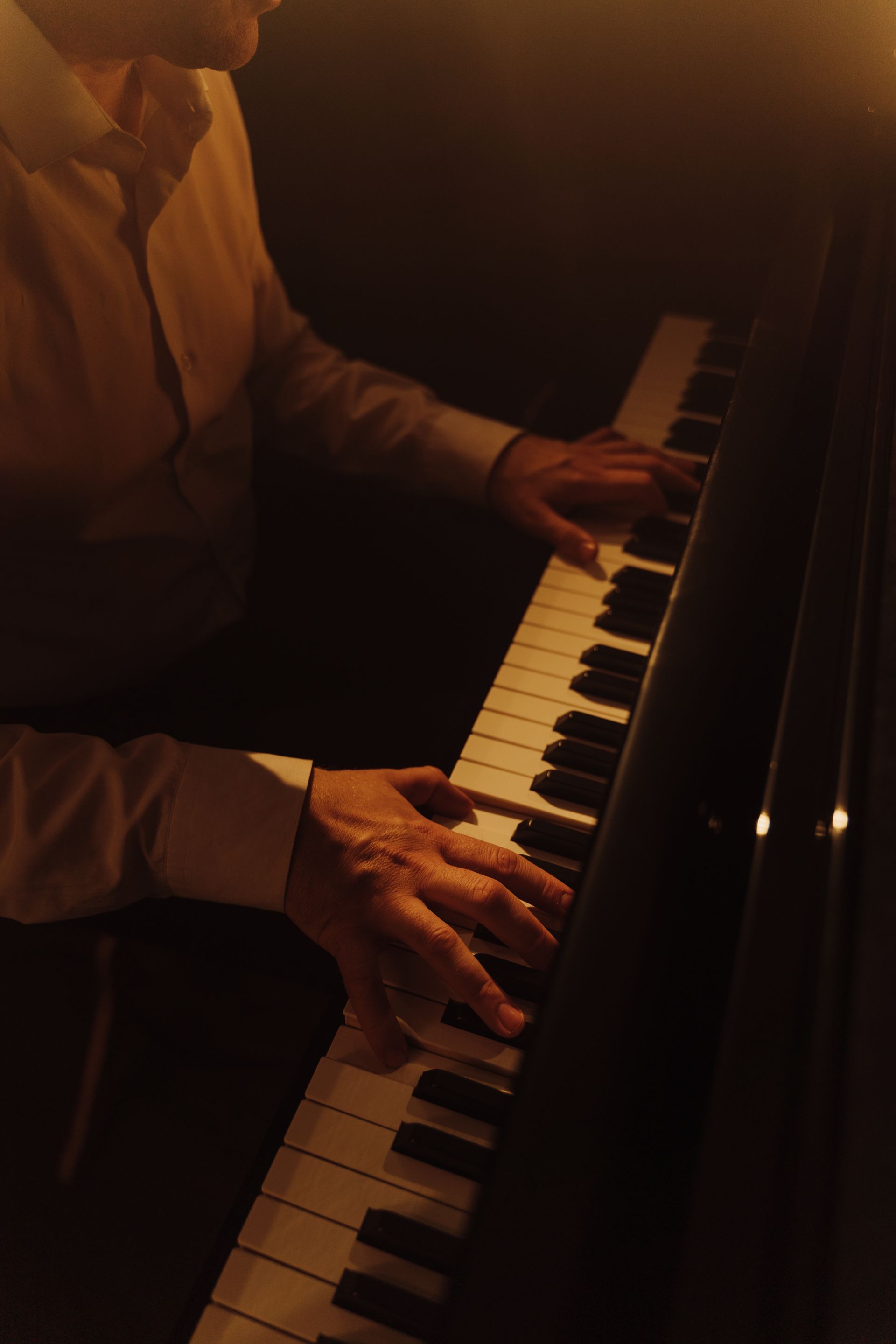A man is playing a piano in a dark room.