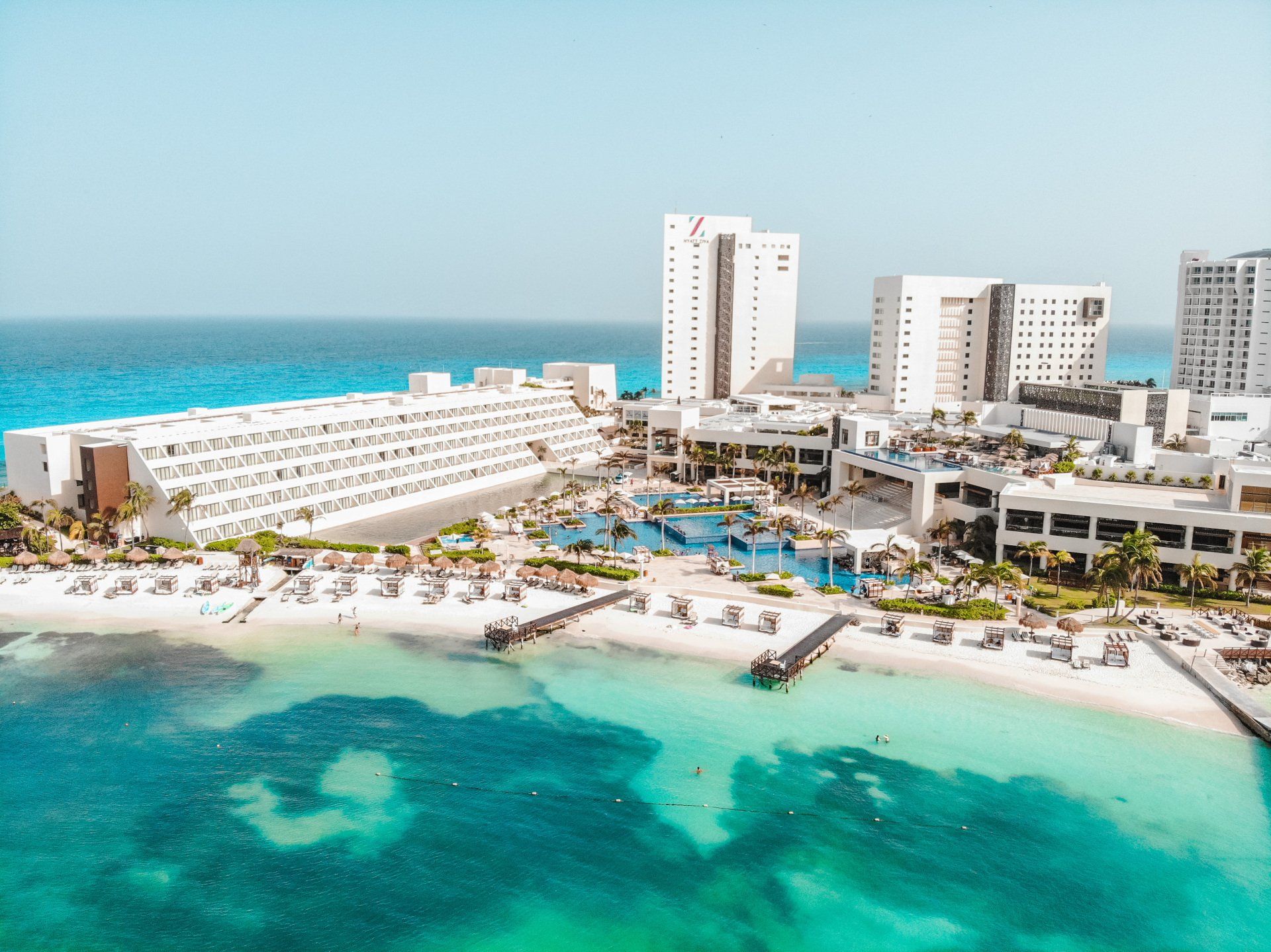 An aerial view of a beach resort with a lot of buildings and a large body of water.