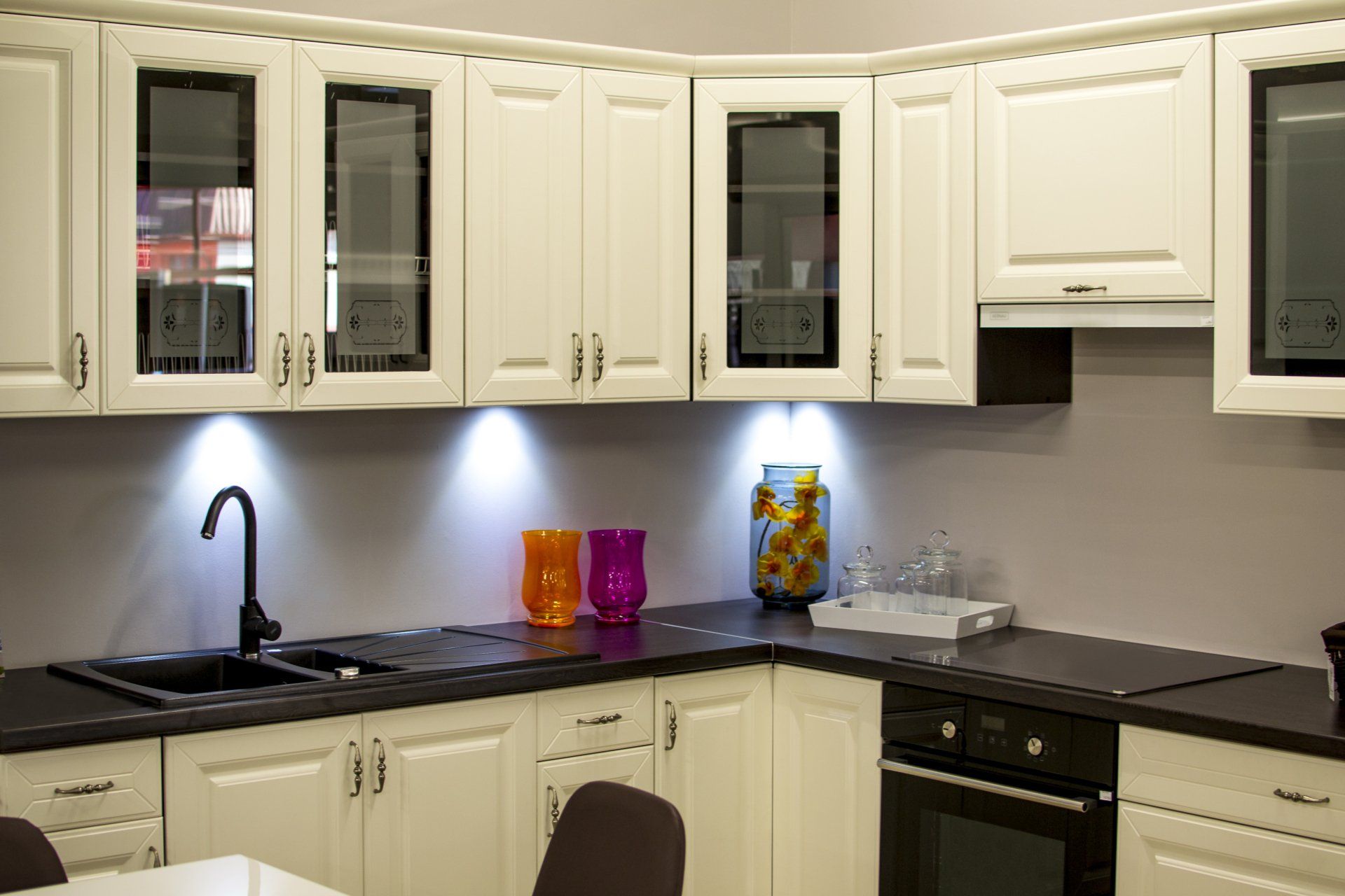 A kitchen with white cabinets , black counter tops , and a sink.