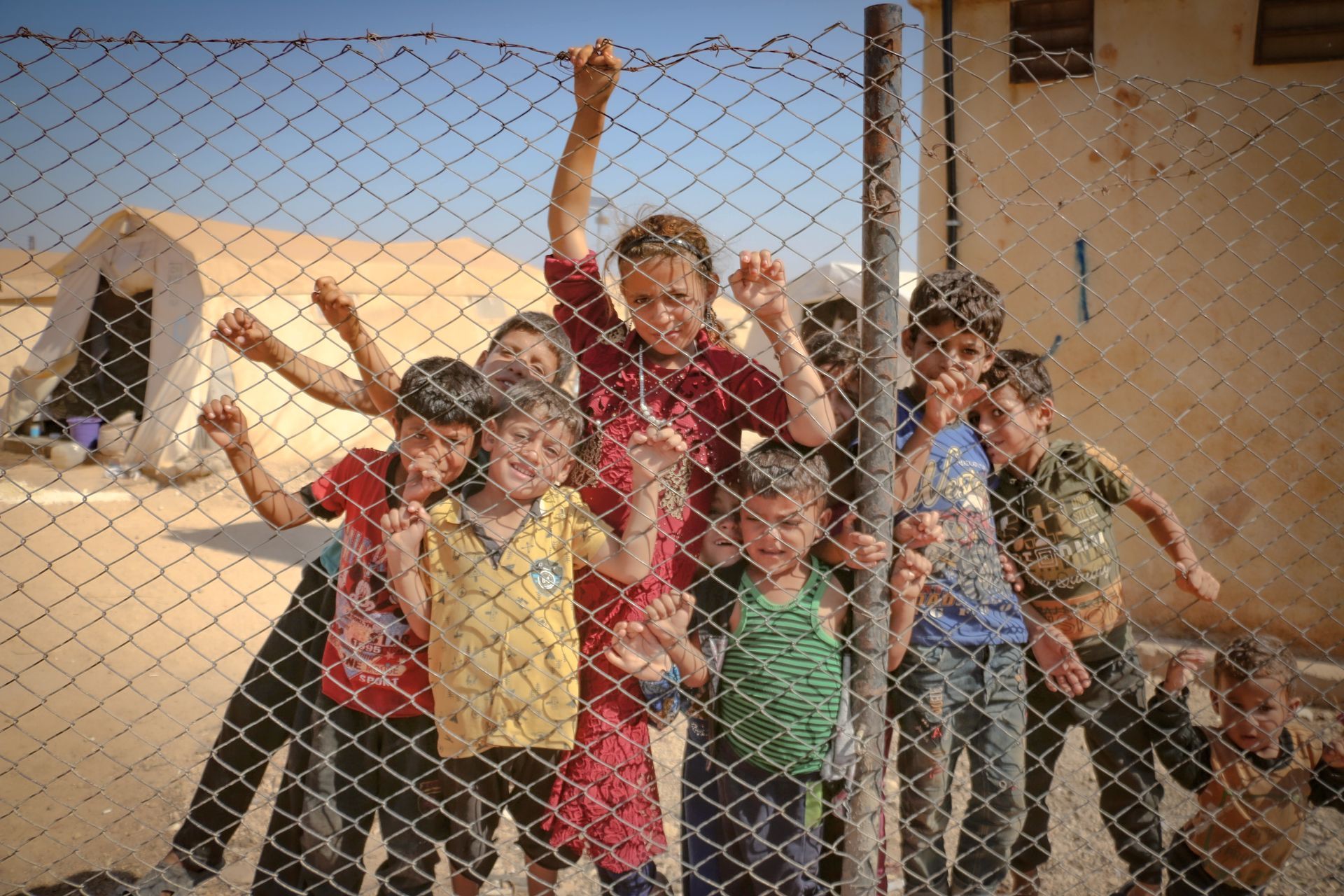 children against a chain link fence, seeking help