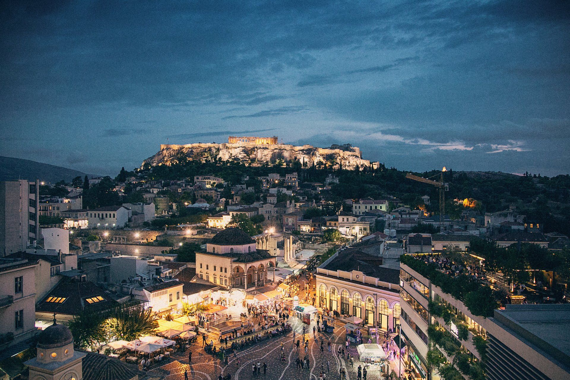 An aerial view of a city at night with a castle in the background.