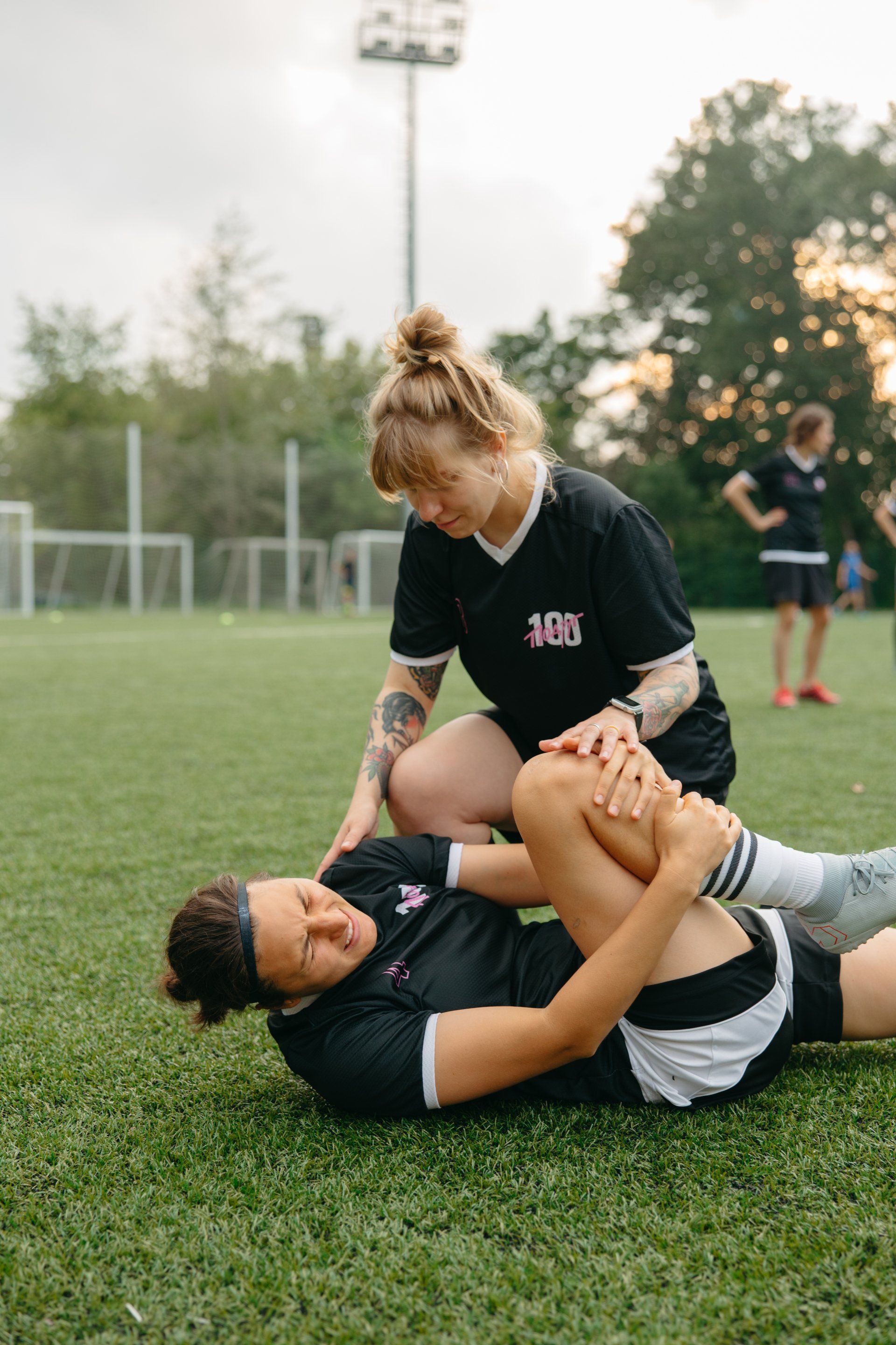 Female soccer player helping injured team player on
