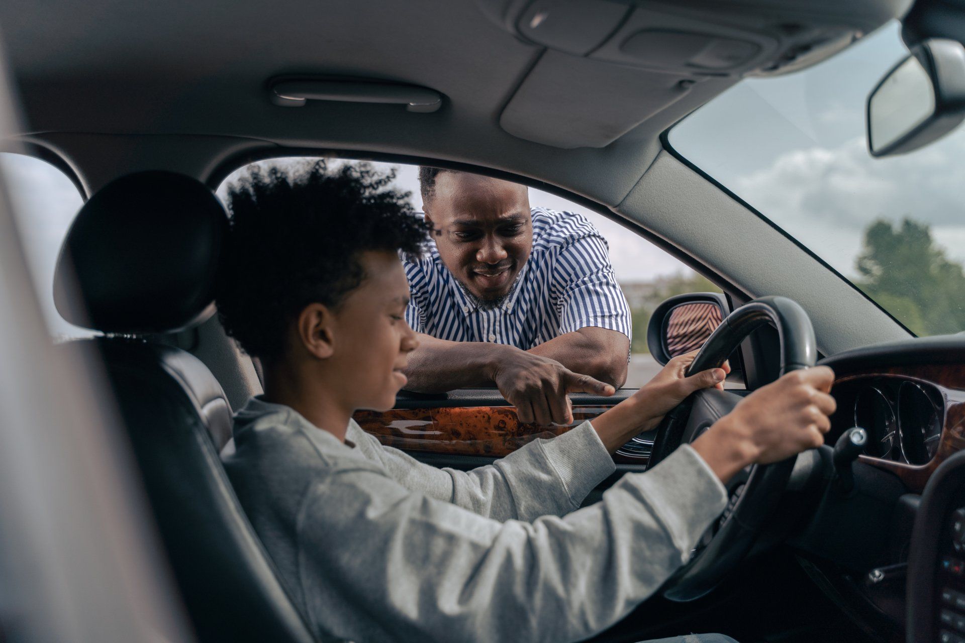 Instructor helping a learner drive a car from the back seat