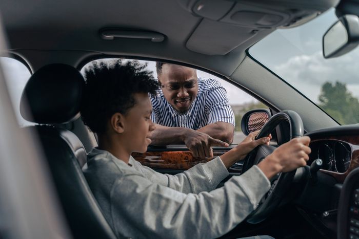 A man is teaching a young boy how to drive a car.