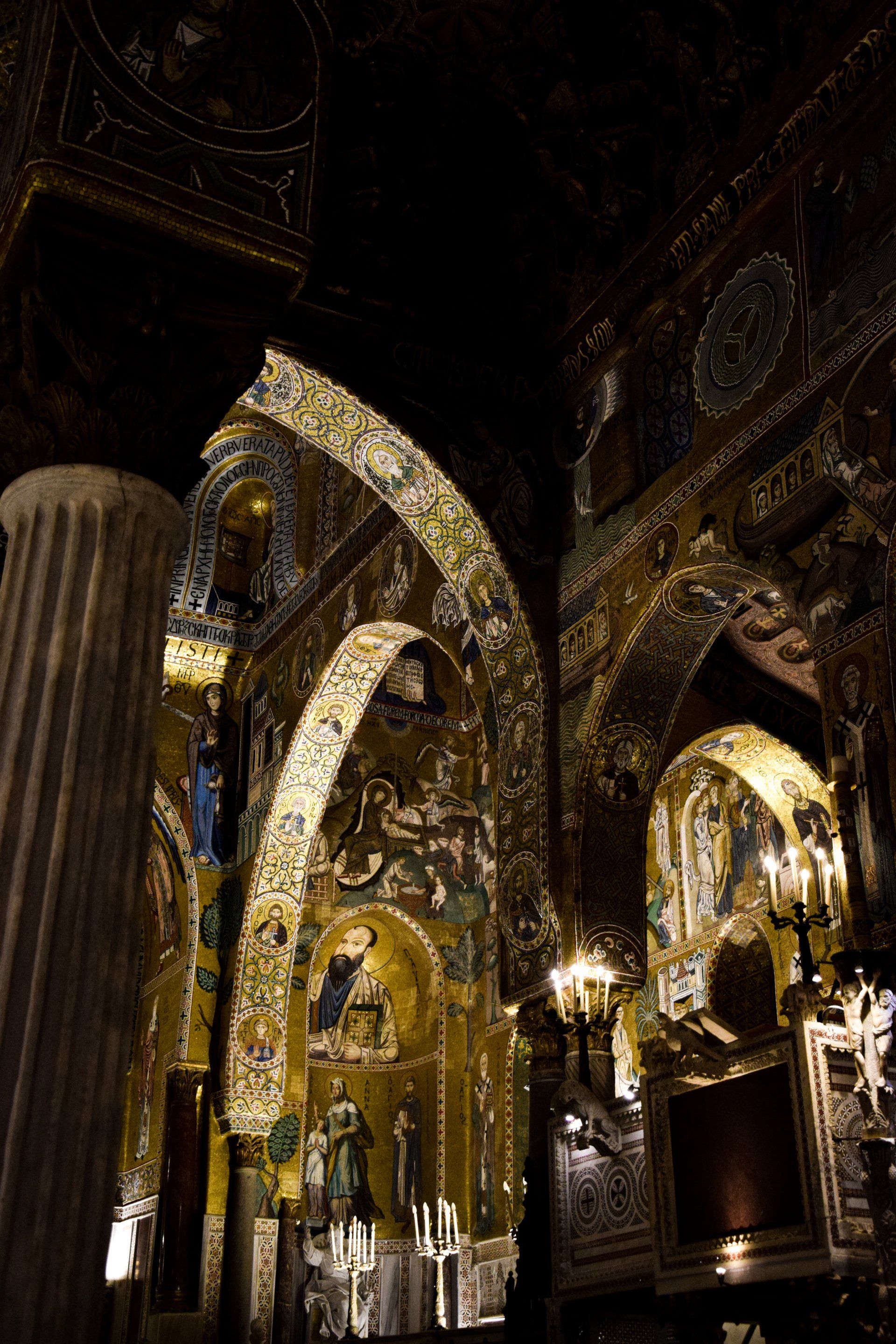 Intérieur orné d'une église avec des mosaïques dorées, des arches et une colonne au premier plan.