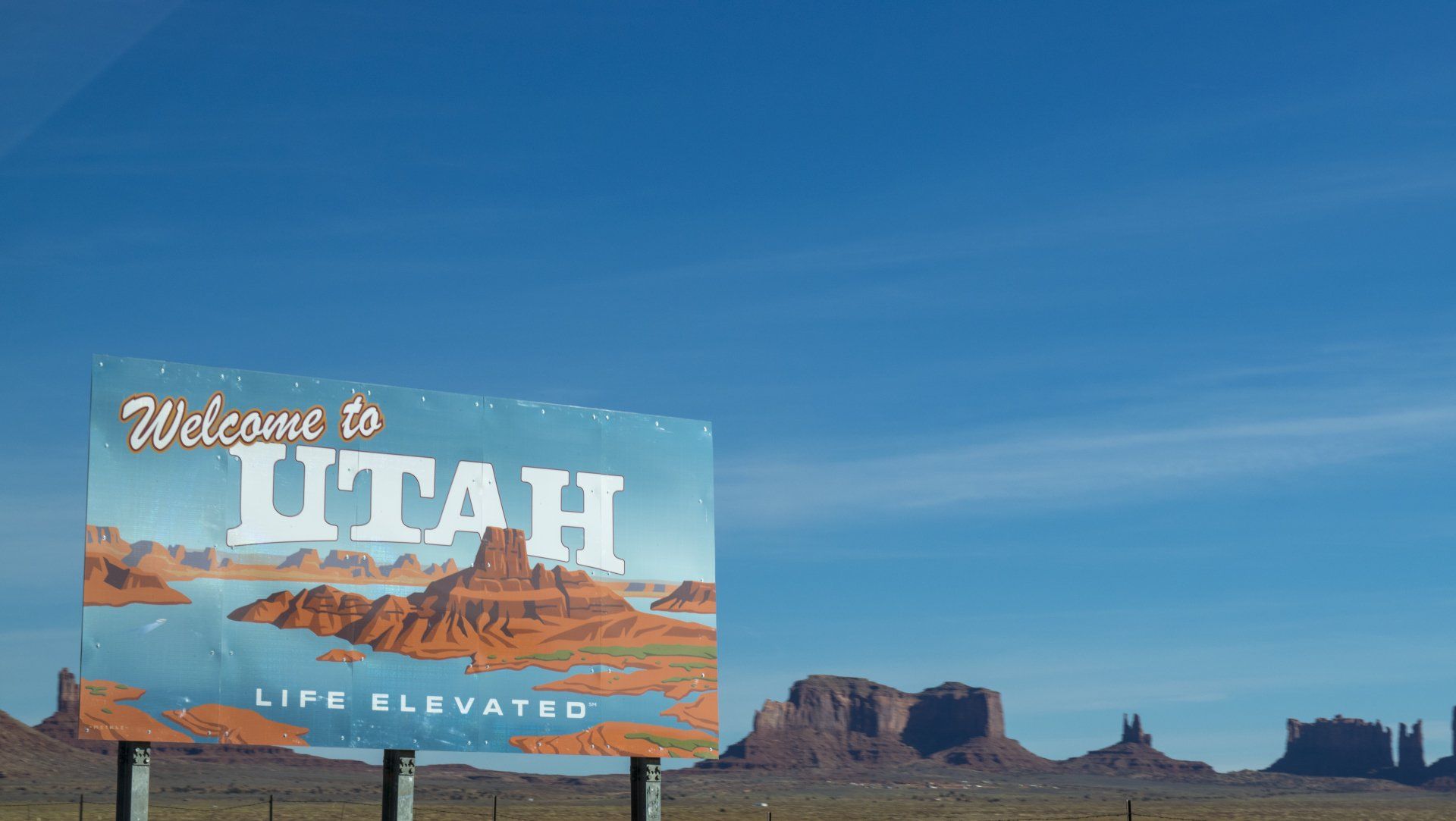 A welcome to utah sign with mountains in the background
