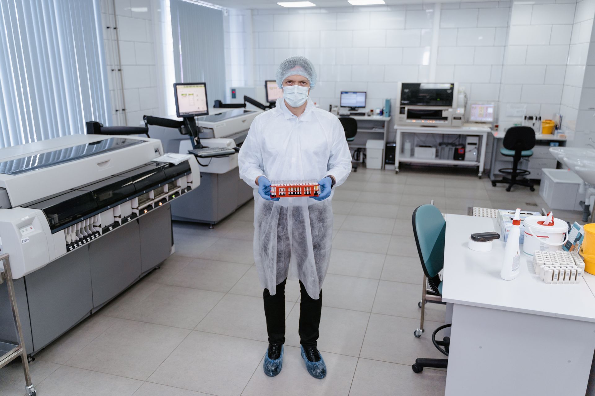 Ein Mann im Laborkittel und mit Maske hält ein Reagenzglas.