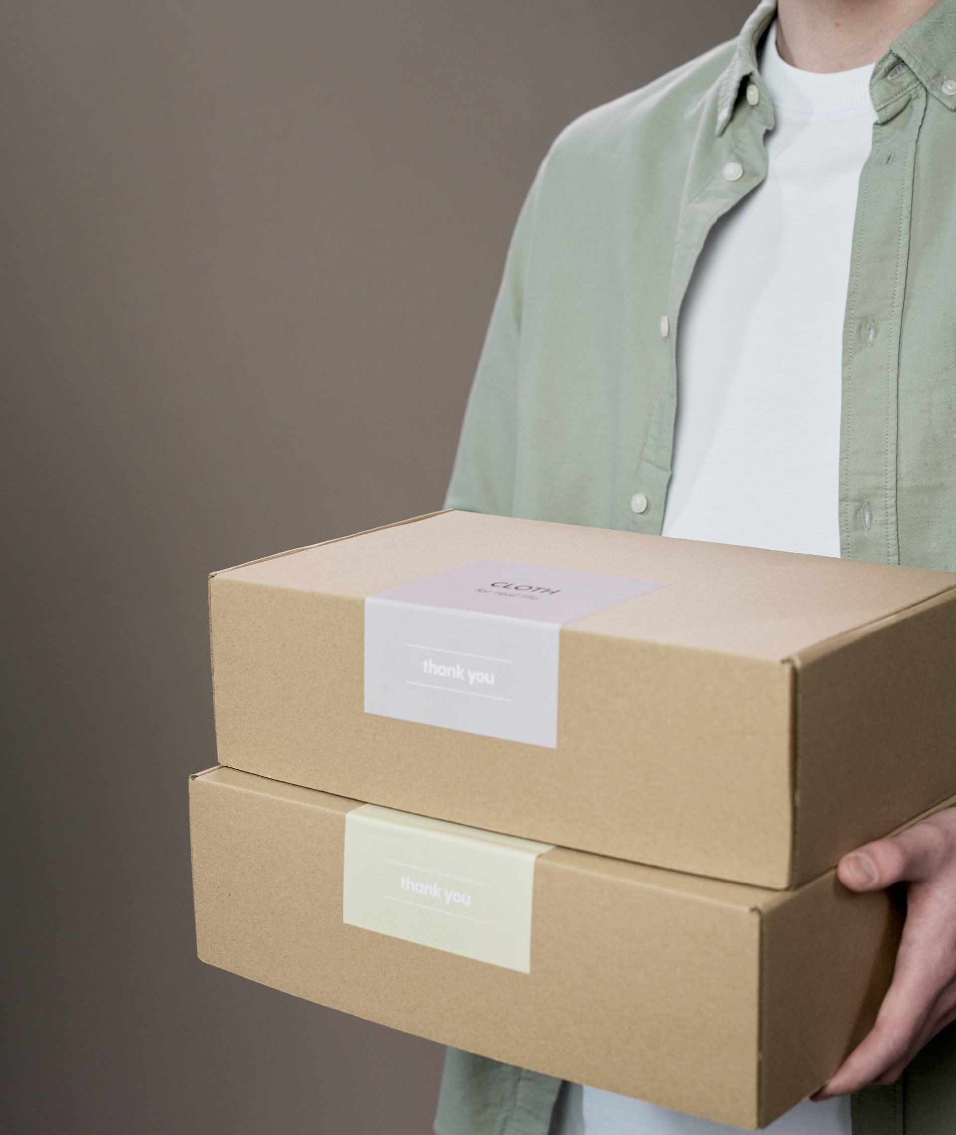A man is holding two cardboard boxes stacked on top of each other.