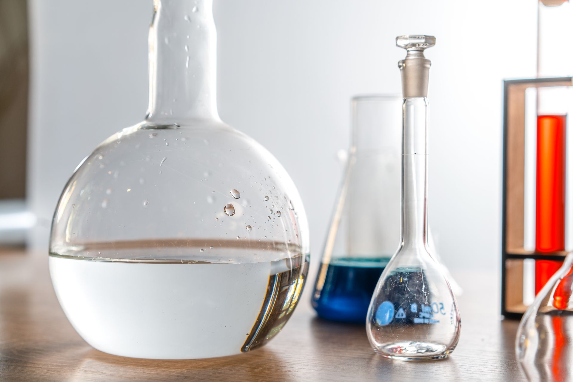 Two beakers filled with liquid are sitting on a wooden table.
