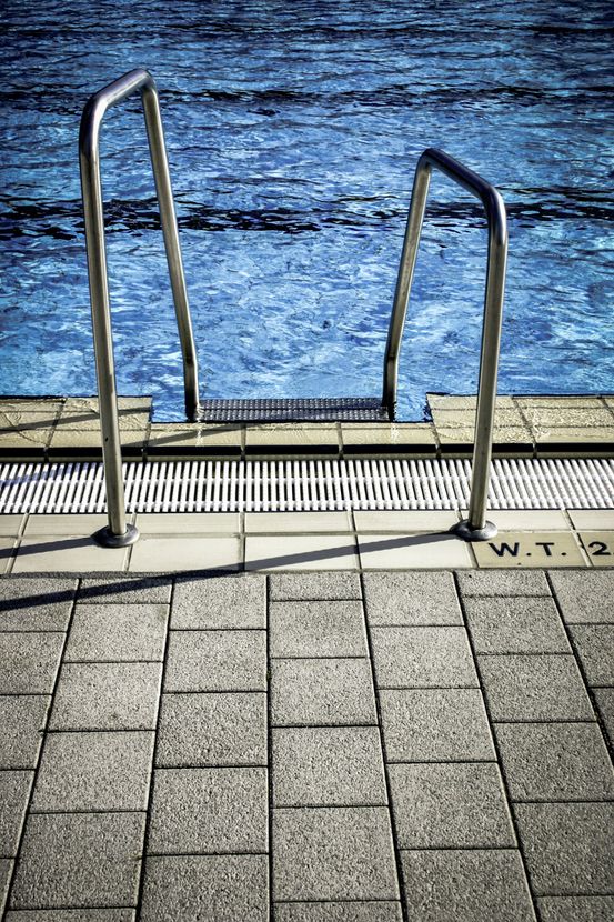 Metal ladder descending from a stone dock into rippling blue water