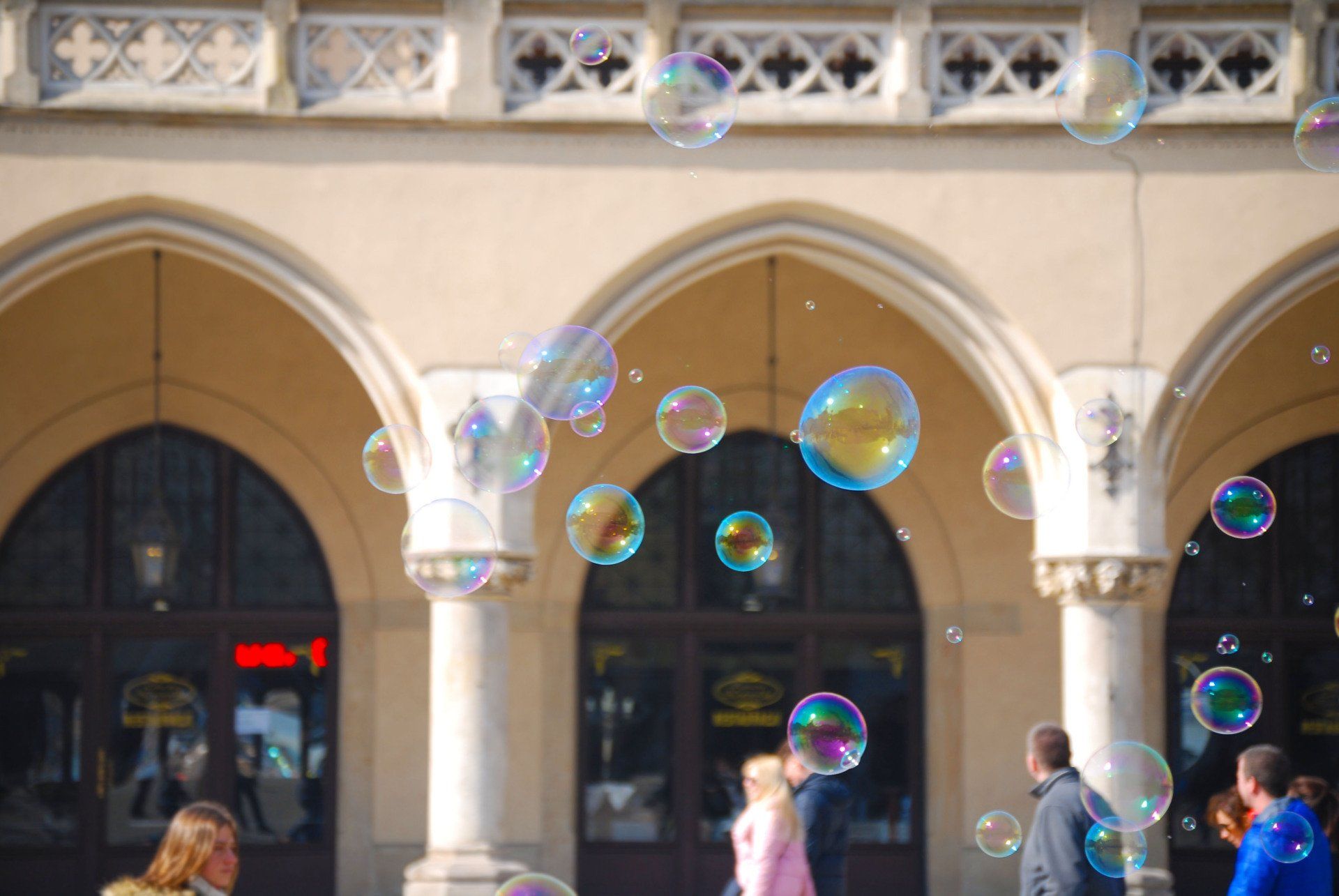 People are blowing soap bubbles in front of a building