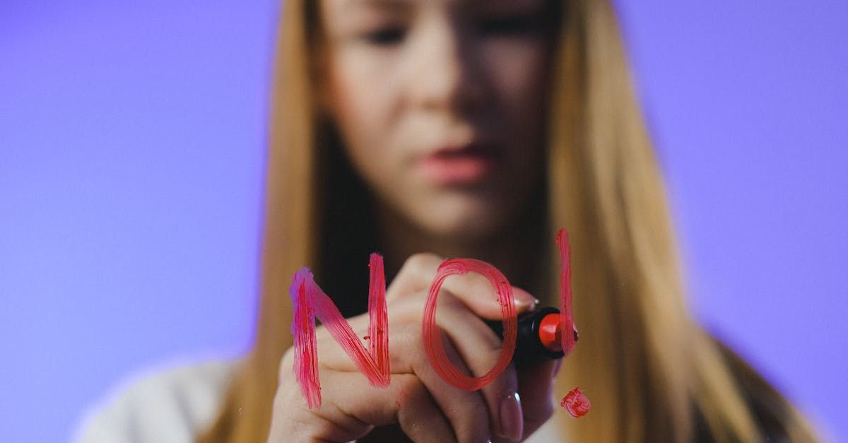 A woman is writing the word no on a glass with a marker.