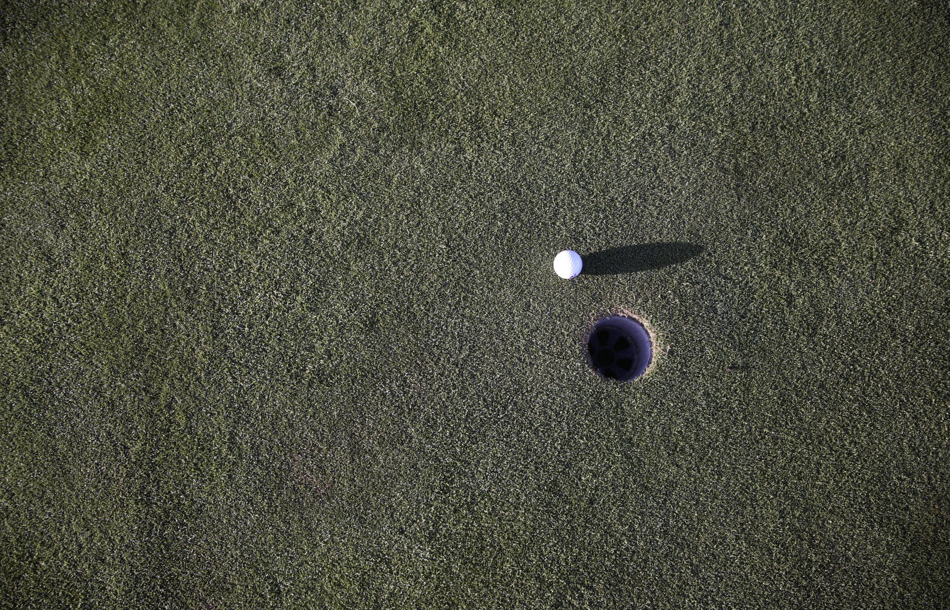 A golf ball is going into a hole on a golf course.