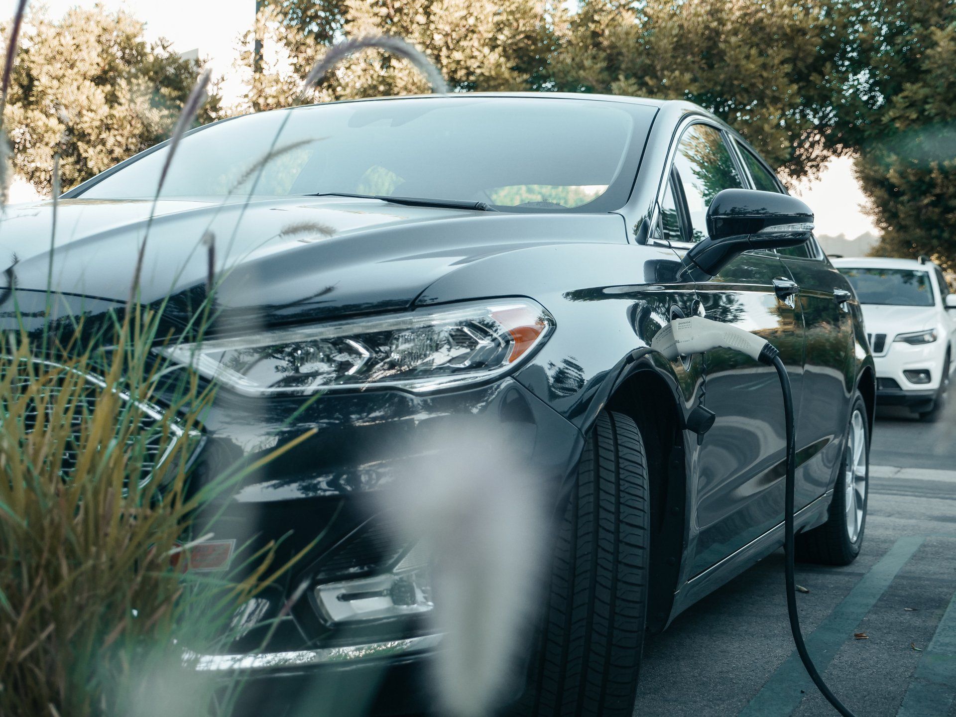 a black electric car is being charged in a parking lot .
