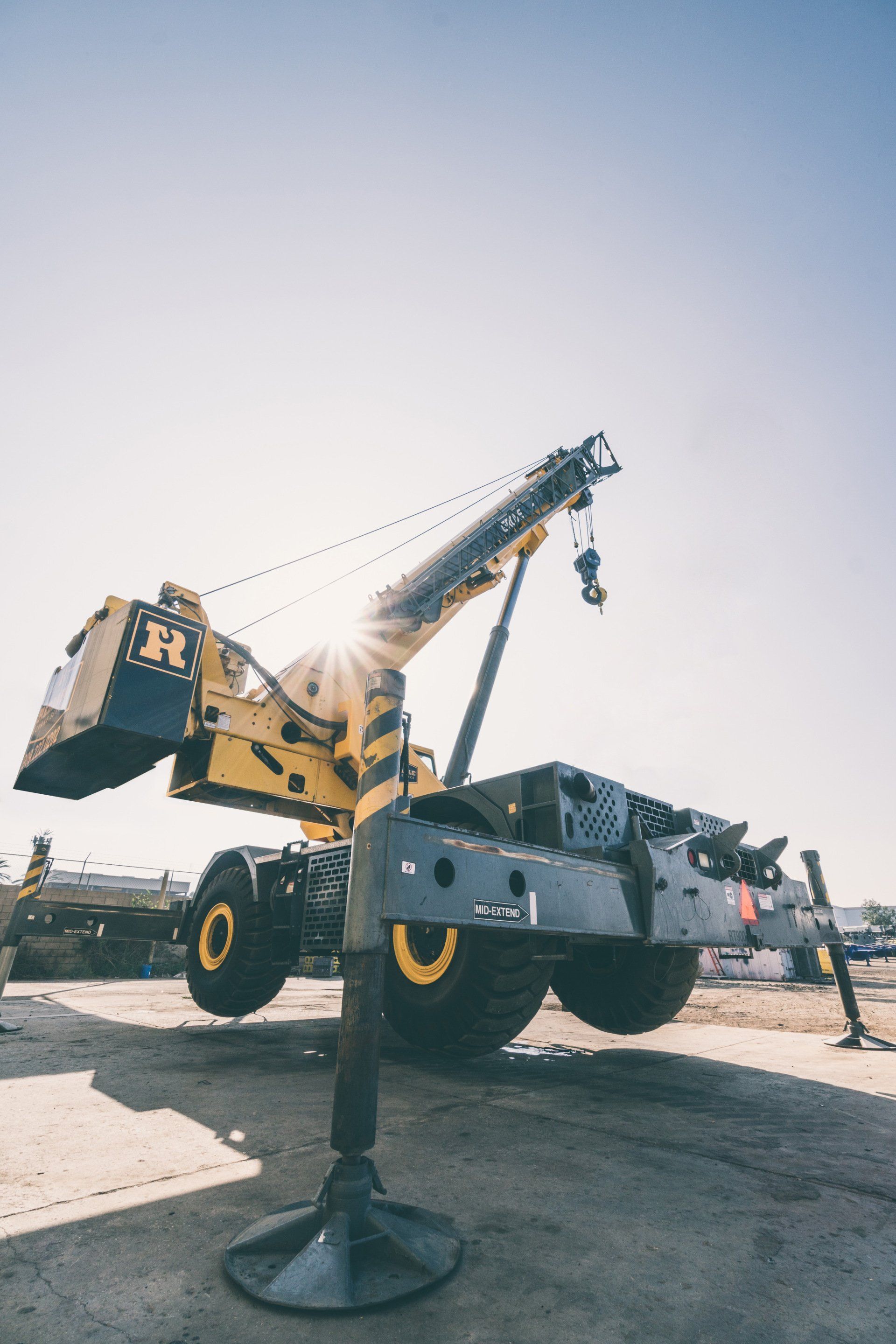 A large yellow and black crane is parked in a parking lot.