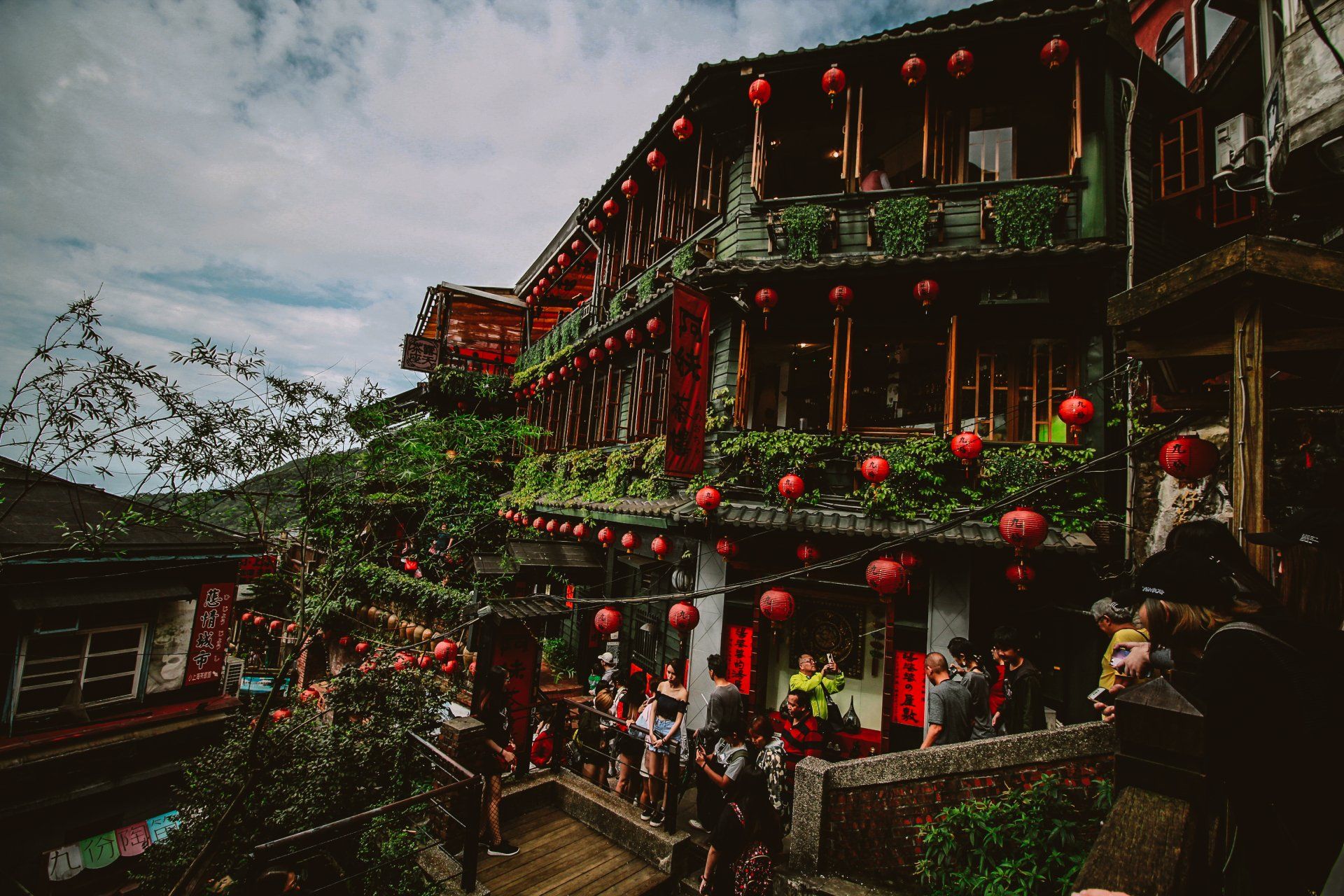 一群人站在一棟掛著紅燈籠的建築物外。