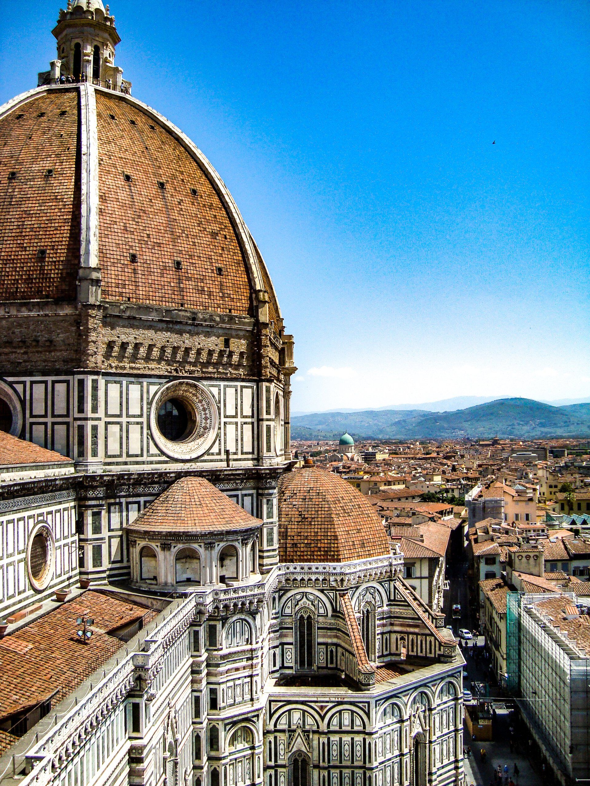 A large dome on top of a building with a city in the background.