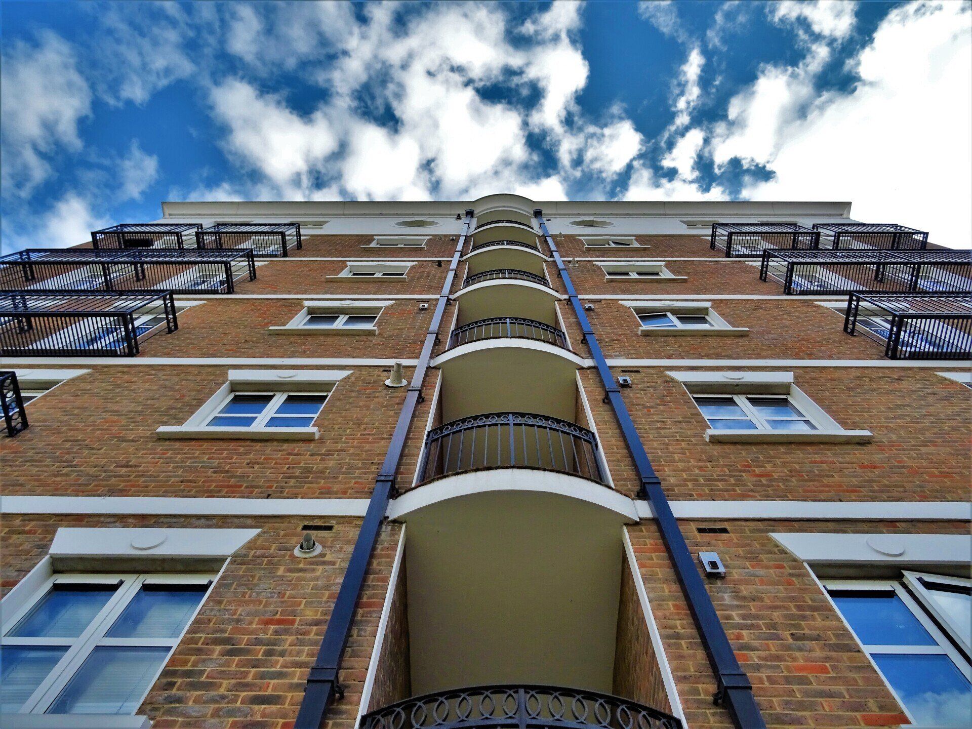 Looking up at a tall brick building with balconies and fire escapes.