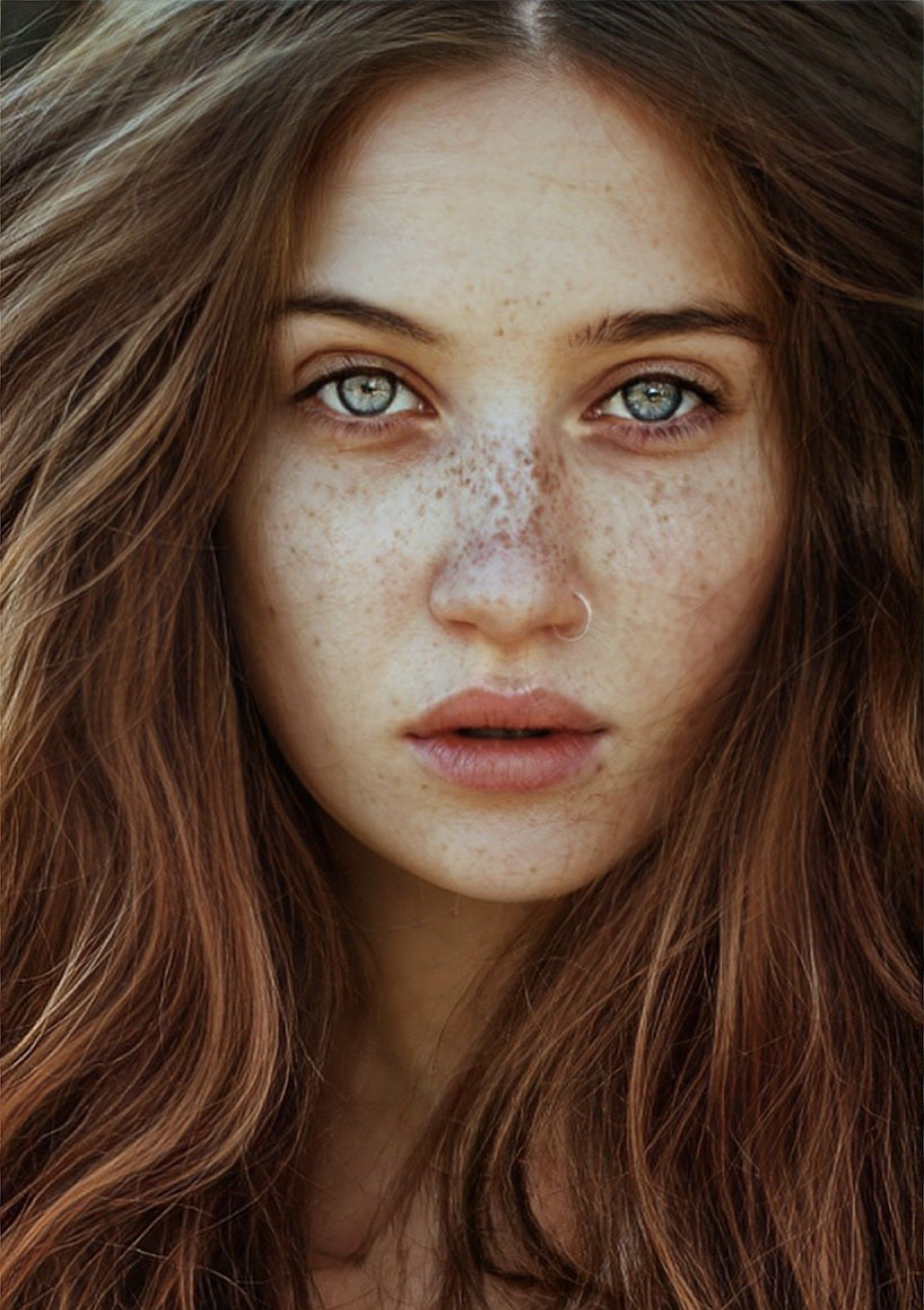 Woman with long auburn hair, blue eyes, and freckles, looking directly at the viewer.