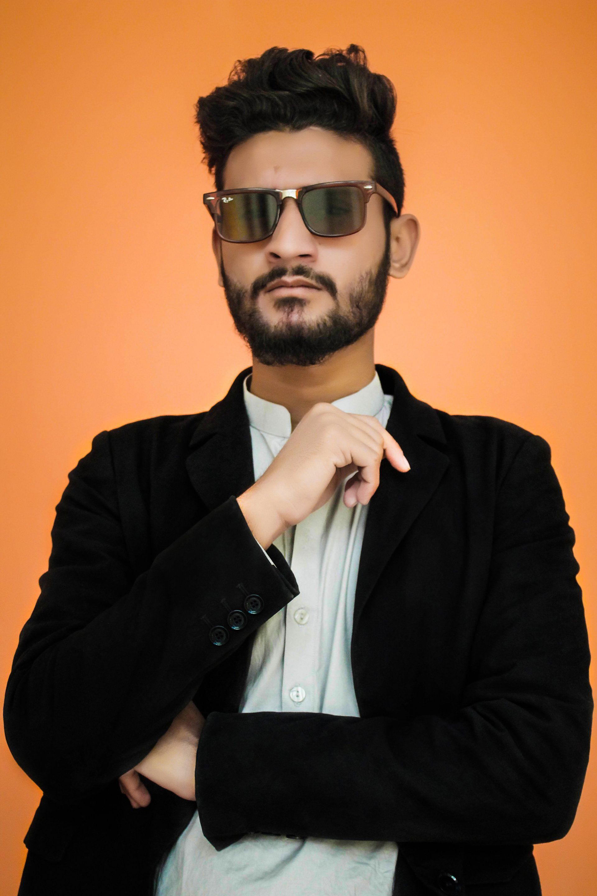 A man with a beard wearing sunglasses and a black jacket.