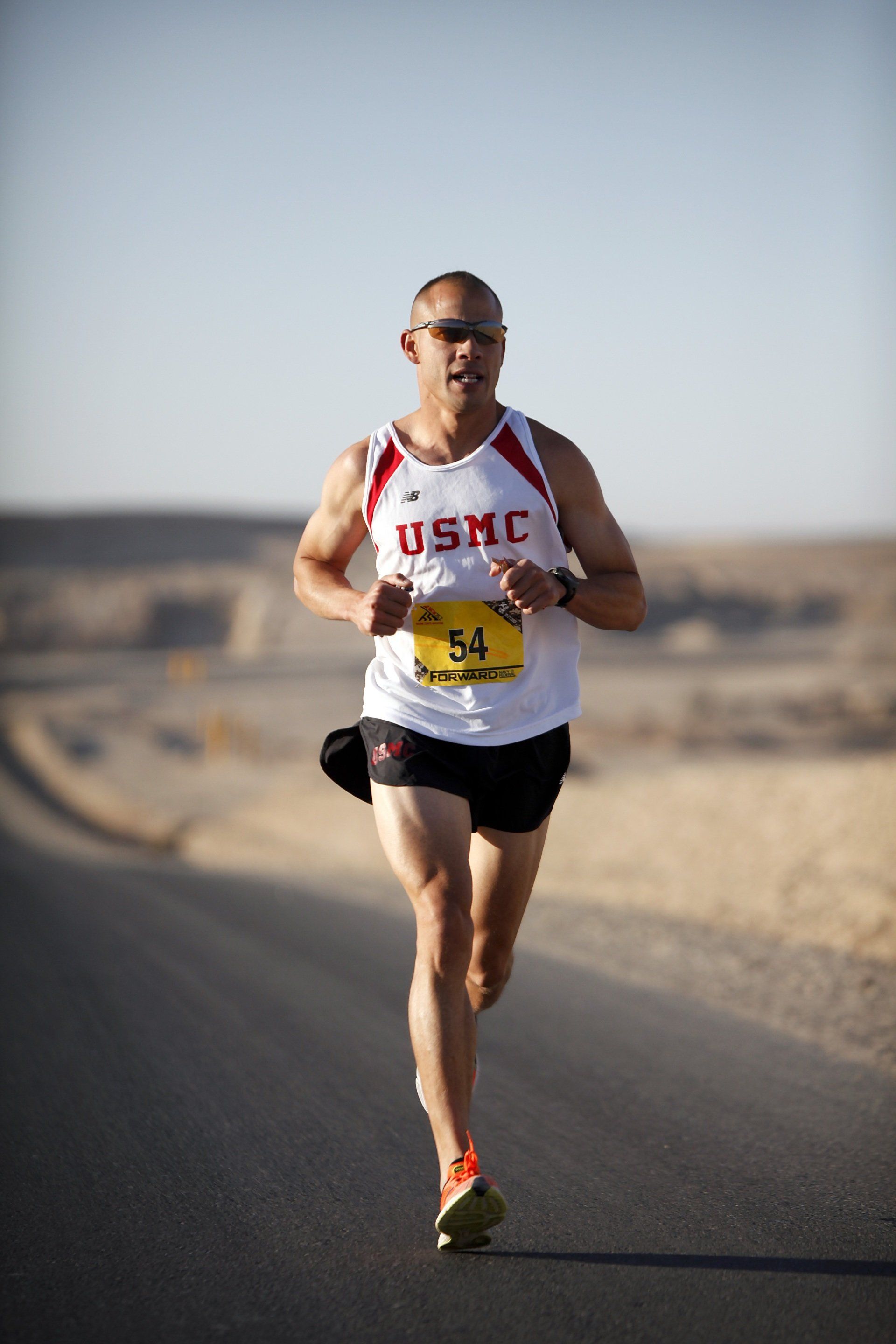 A man in a usmc shirt is running down a road