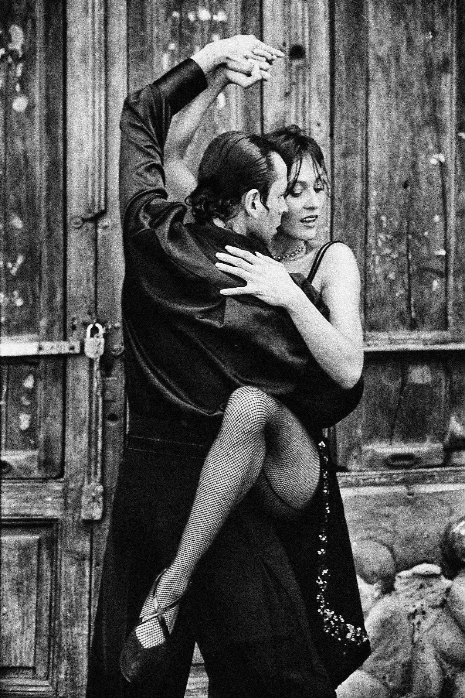 A man is holding a woman in his arms while dancing tango