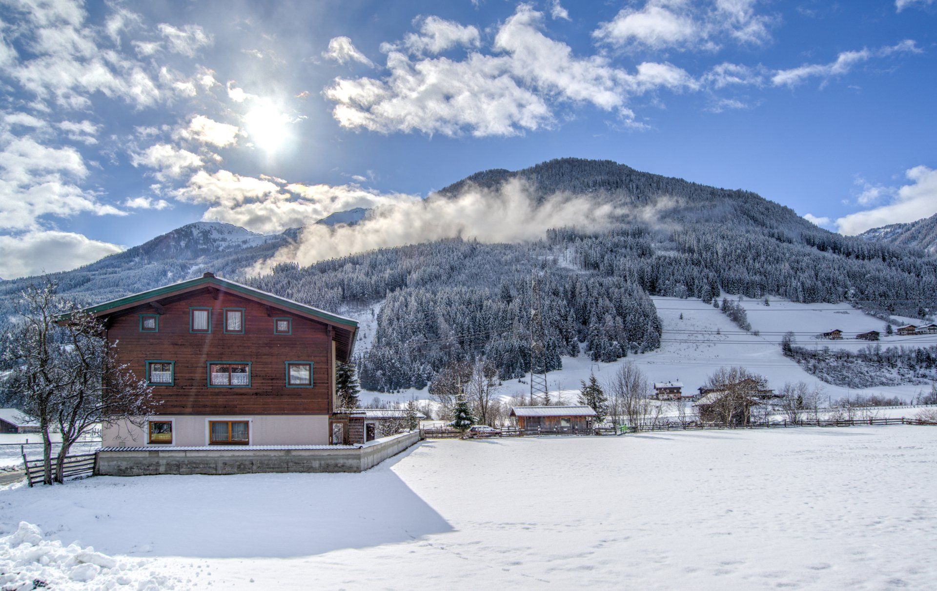 Village de montagne enneigé avec une maison rouge sous un ciel d'un bleu éclatant