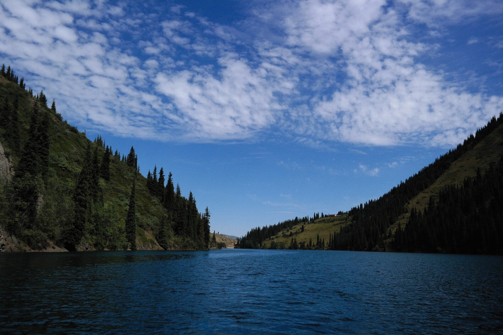 A lake surrounded by mountains and trees on a sunny day