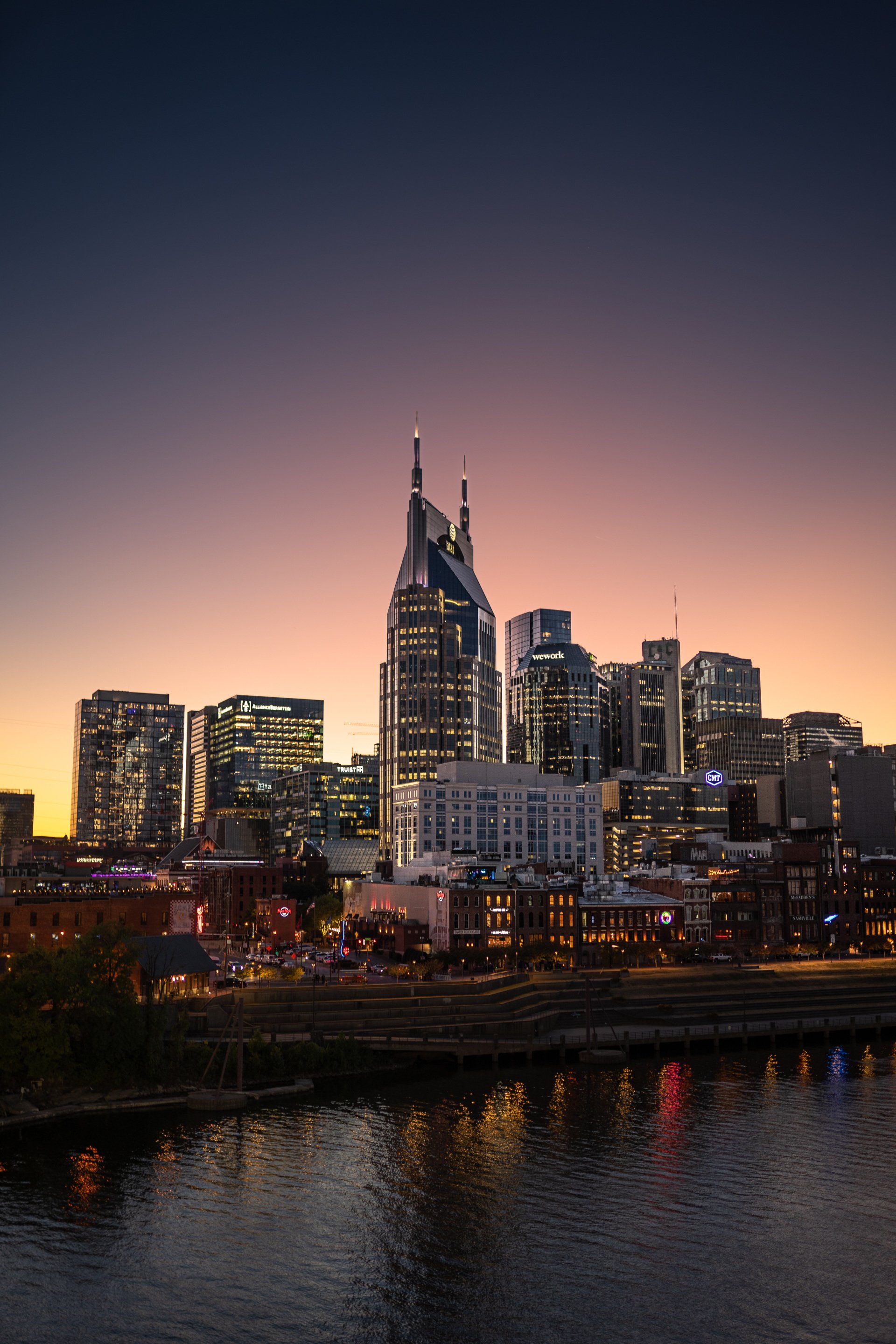 A city skyline at night with a river in the foreground.