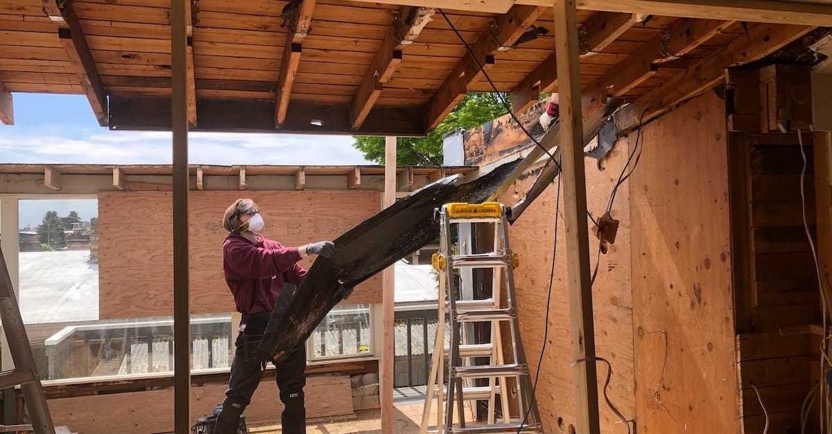A man wearing a mask is standing in front of a building under construction.