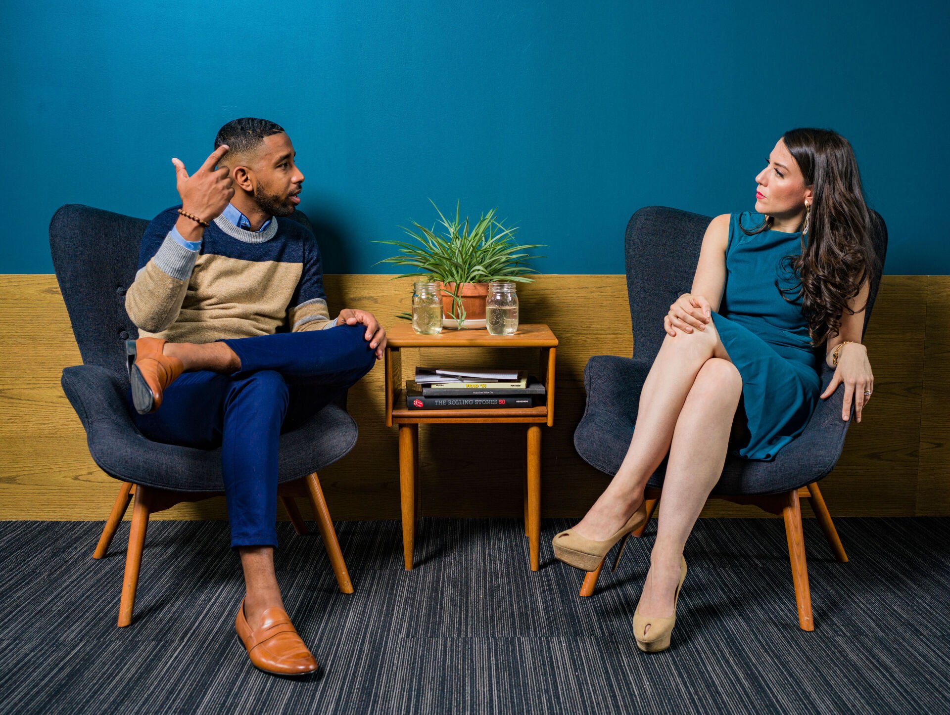 A man and a woman are sitting in chairs talking to each other