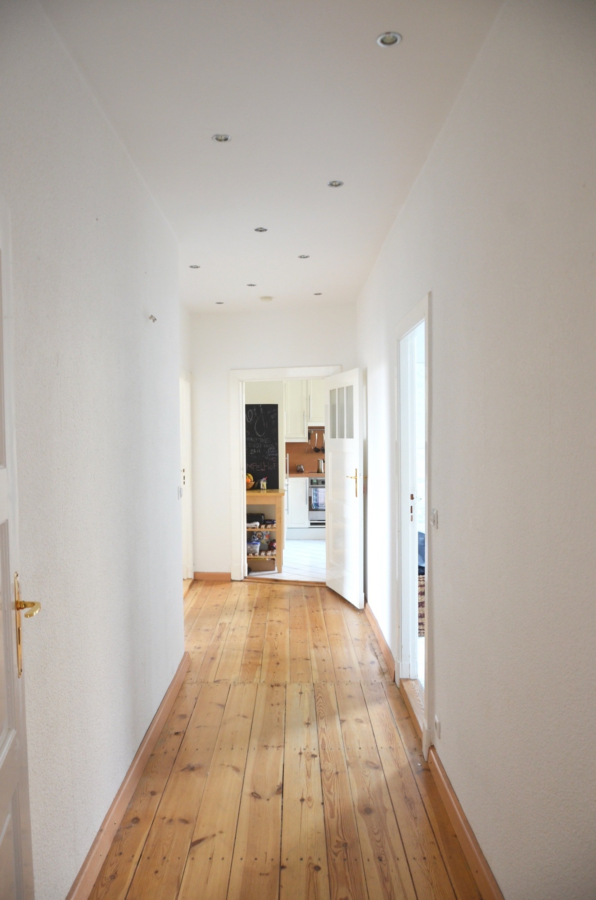 A long hallway with wooden floors and white walls