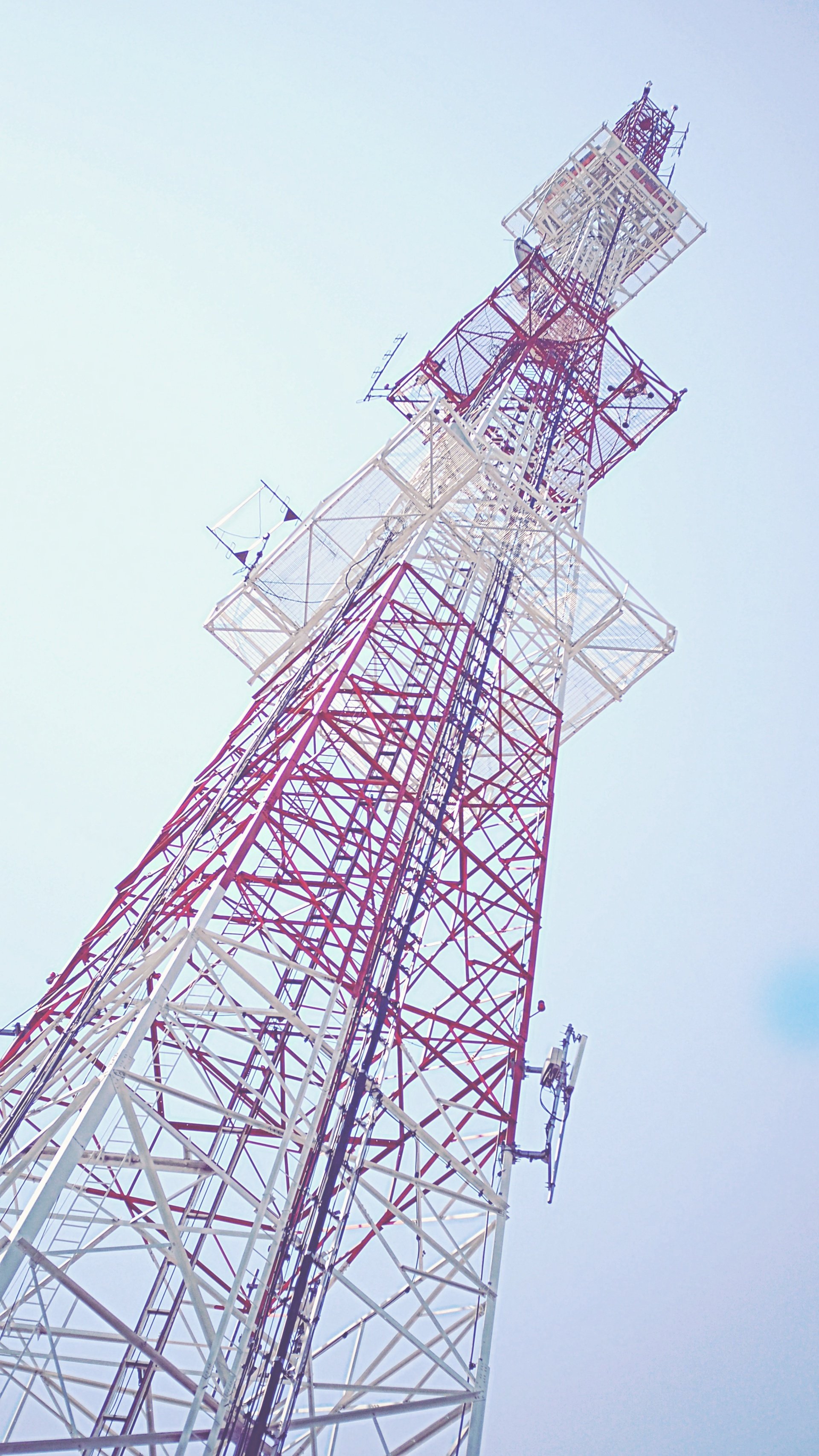 A red and white telephone tower against a blue sky.