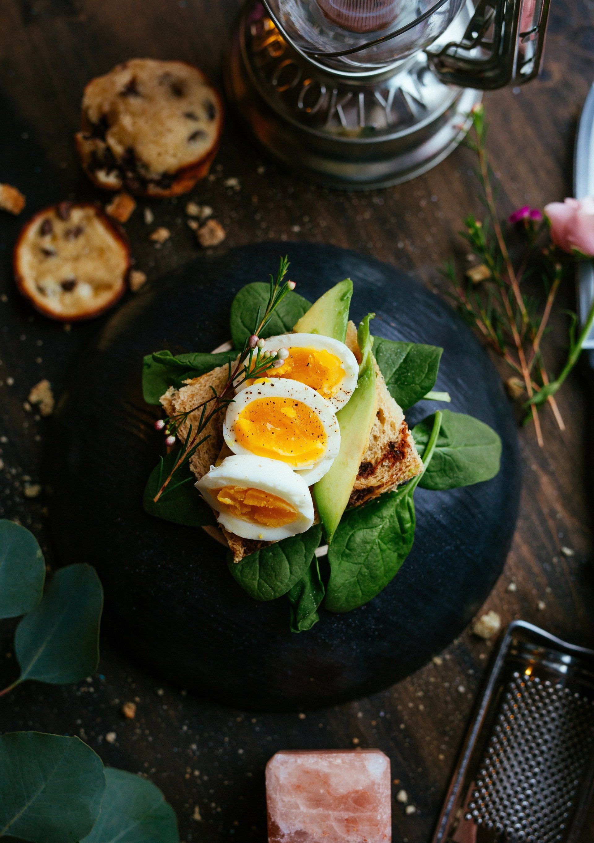Open sandwich met gekookte eieren en groenten op een donker bord, geserveerd op een rustieke tafel.
