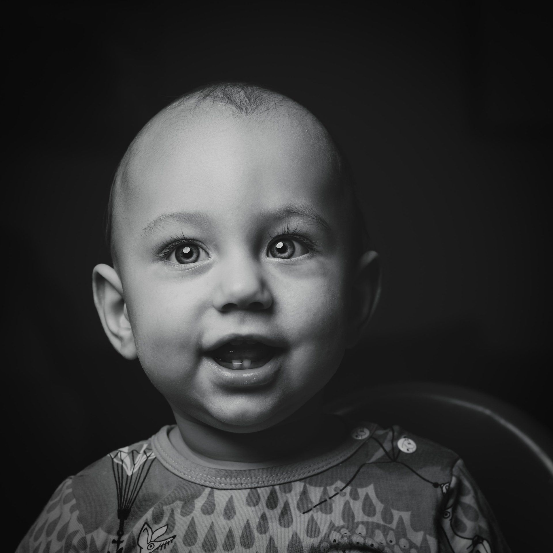 A baby is smiling in a black and white photo.