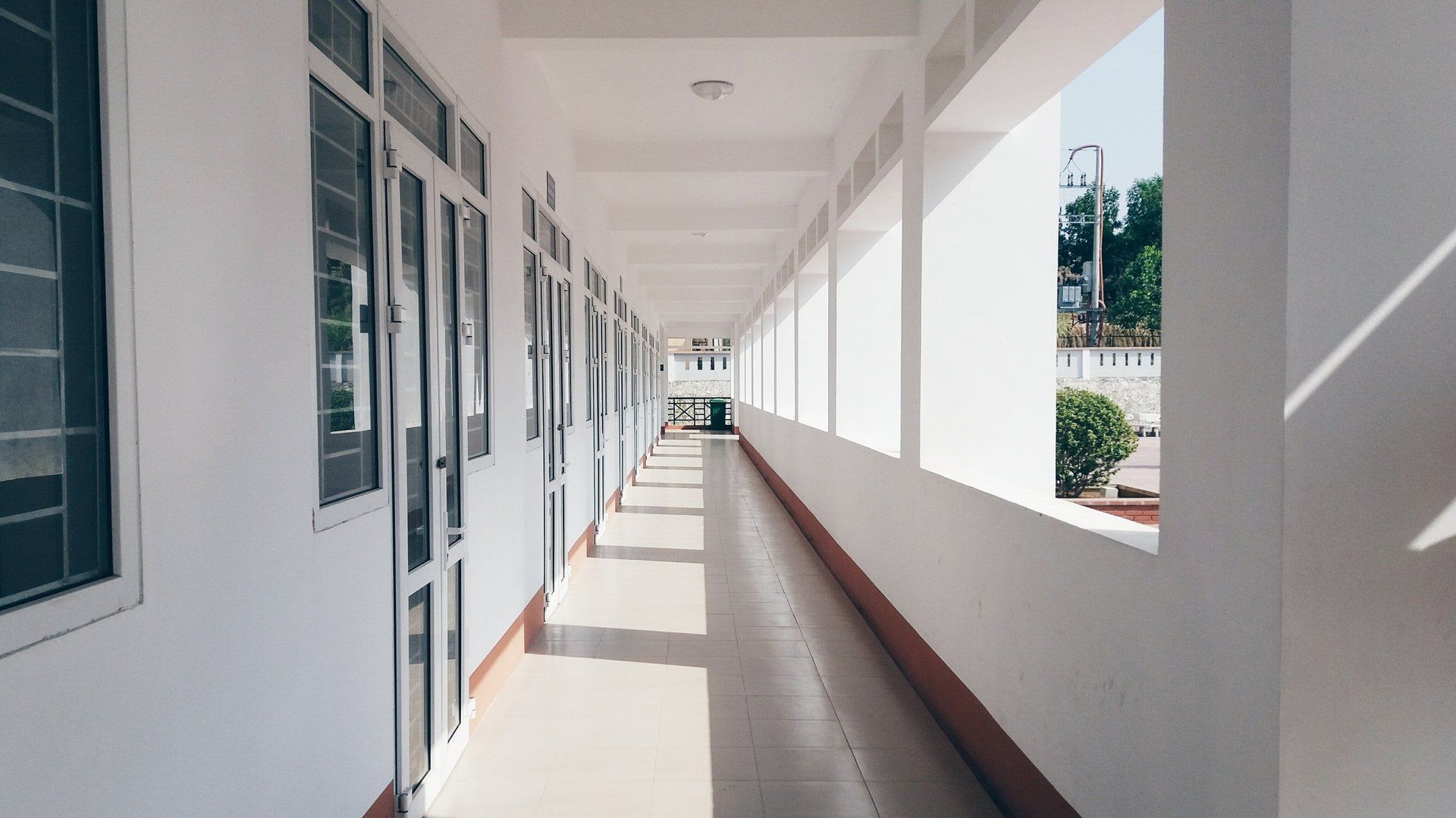 A long hallway in a building with a lot of windows and doors.